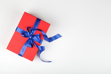 red gift or present box with blue ribbon on white background.