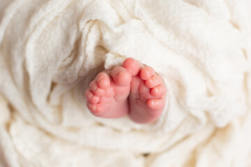 a small leg of the newborn in a white scarf. soft focus