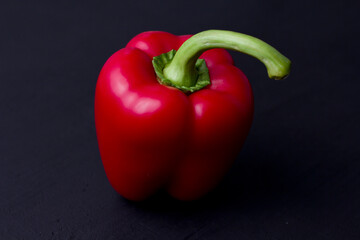 Red bell pepper lies on a black background. Flat lay, top vie