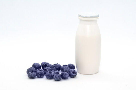 Natural yogurt with probiotics and Lactobacillus in small plastic bottle and Blueberry on white background. Healthy diet food, dairy products with fruit and berry additives. Selective focus
