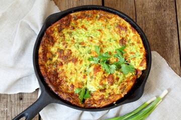 Casserole with zucchini in a frying pan on a wooden table