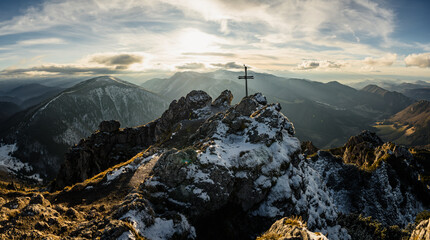 Christian cross on the top of the hill, Big Rozsutec with sun between the clouds in the background...