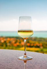 A glass of white wine with lake Balaton in the background.