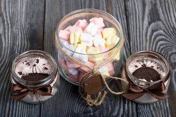 Marshmallow in a jar. With cookies and chocolate. On pine boards.