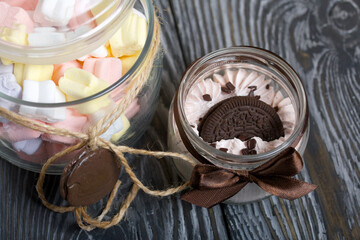 Marshmallow in a jar. With cookies and chocolate. On pine boards.