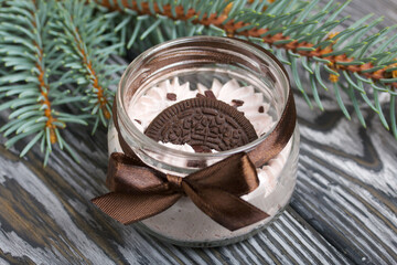 Marshmallow in a jar. With cookies and chocolate. Nearby is a spruce branch. On pine boards.