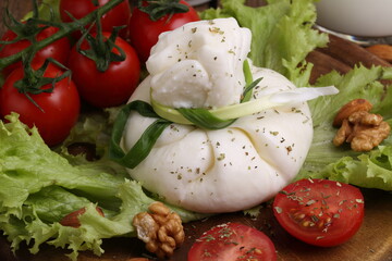 Burrata with tomatoes and cream on lettuce leaves