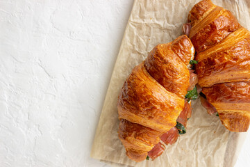Croissants sandwiches with prosciutto, basil and white cheese. French cuisine. Breakfast.