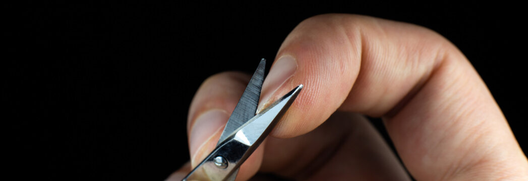 Man is making a manicure scissors. Procedures at home. Cutting nails.