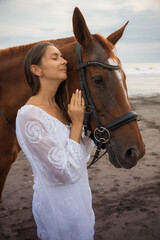 Portrait of beautiful woman and brown horse. Caucasian woman hugging and stroking horse. Love to...