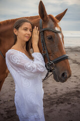 Portrait of beautiful woman and brown horse. Caucasian woman hugging and stroking horse. Love to animals. Beach in Bali, Indonesia