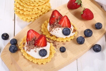 Mascarpone cheese with strawberries and blueberries on a white wooden table