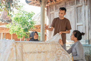 Obraz na płótnie Canvas a man who teaches both women how to use canting for the draw batik