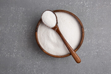 Closeup collagen powder in a wooden plate with a spoon or measuring quantity on concrete background. f Extra protein intake. Natural supplements for beauty.