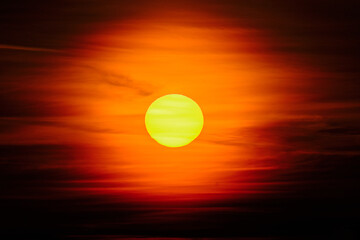 Close-up sunset through the clouds. Big orange sun.