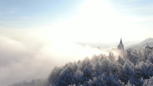 Aerial view of castle in foggy weather. Drone flight above low hanging clouds.