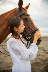 Obraz premium Portrait of beautiful woman and brown horse. Caucasian woman hugging and stroking horse. Love to animals. Beach in Bali, Indonesia