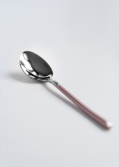 Silver or steel cutlery on an isolated background. Gilded teaspoon of pink color. Top view.