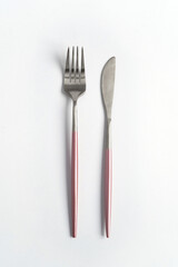 New luxury silver or steel cutlery view from above on a isolated white background. Top view. Pink knife and fork for a festive table for a wedding, birthday or party.