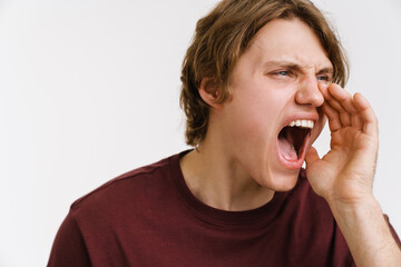 Angry young man screaming loud, looking away isolated