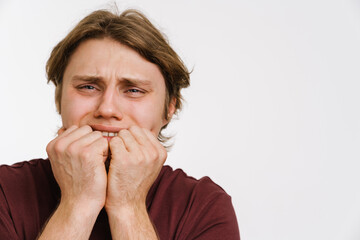 Young scared man covering face with hands isolated