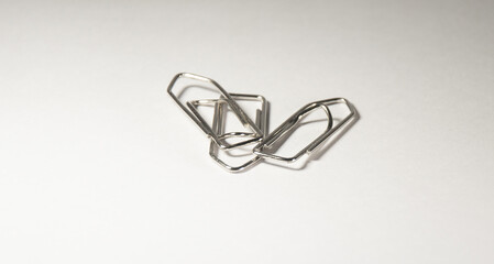 Closeup picture of paperclips on isolated background. Paper silver color pins with a shadow