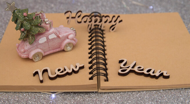 pink car with christmas tree and gifts on open notepad on gray background.new year.