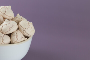 meringues in a bowl on a purple background