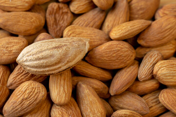 A lot of almonds and one unpeeled peeled nut. Natural background for healthy eating concept.