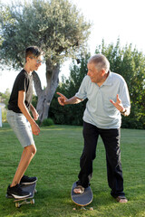 nonno con nipote giocano con gli skateboard nel prato di casa