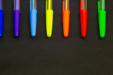Colored pens with caps on a black background