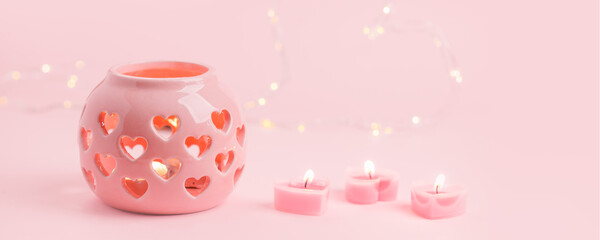 St. Valentine's day burning candles and pink cearmic candlstick on pink background, stylish monochrome holiday card with copy space, romance february day, mother, woman day
