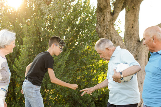 Nonno e nipote giocano "a pari e dispari" con la palla in mano nel giardino di casa