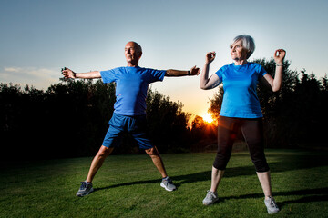due  anziani con abbigliamento da ginnastica si allenano in un prato verde al tramonto
