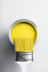 Demonstrating colors of year 2021 - Gray and Yellow. Brush with white handle on open can of yellow...