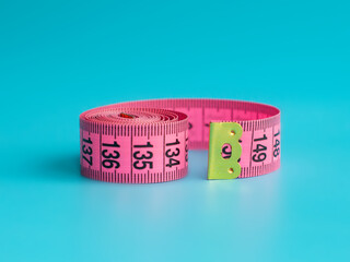 Pink centimeter tape measure on blue background