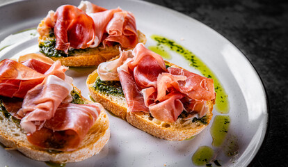 Bruschetta with prosciutto and pesto sauce on plate