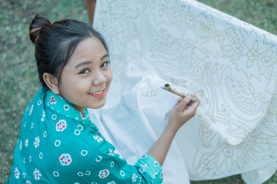 portrait young woman drawing batik on a white cloth using canting