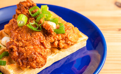 Homemade Southern American comfort street food fresh deep fried crispy stacked chicken wings with buffalo red chili spicy hot sauce and waffle sweet maple syrup
