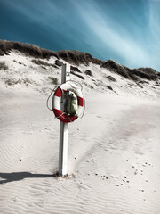 Denmark landscape with white sand, blue sky and red and white lifebuoy. Travel wallpaper