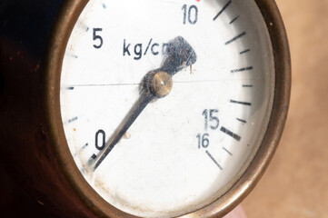 Close-up of an old industrial pressure gauge display with worn protective glass. Macro