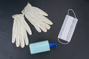 Medical mask, gloves and soap dispenser on black background