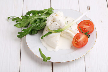 Burrata cheese with tomatoes on a white wooden background