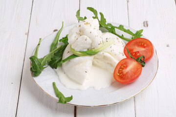 Burrata cheese with tomatoes on a white wooden background