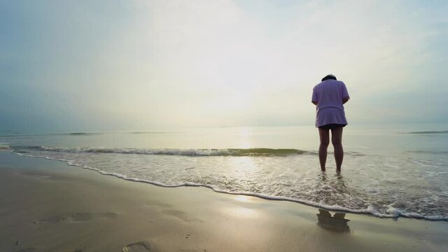 4K VDO backside solo asian woman relax and take photo by her phone on beach with happiness and joyful in summer