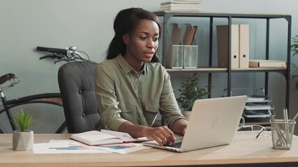 Happy female office worker having fun sitting at her desk celebrating the successful completion of business deal.