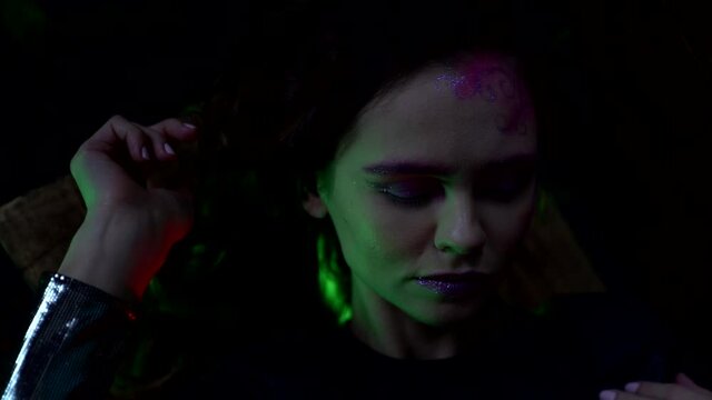woman with shiny fashion makeup is posing in darkness, slow motion closeup portrait