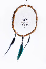 Fototapeta premium Home decoration - handmade round dream catcher made of willow vines, white threads, beads, and colored feathers on a white background. Scandinavian style.