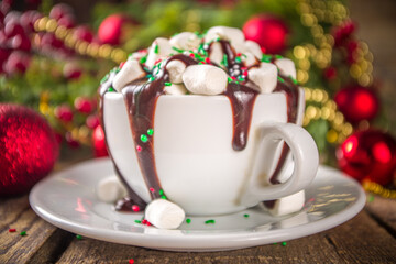 Christmas hot chocolate. Crazy shake styled hot chocolate cup with a lot of marshmallow, chocolate drizzles and green red sugar sprinkles, Christmas New Year decorate background festive bokeh effect