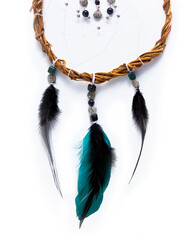 Part of a Dreamcatcher made of willow branches and green, black feathers, placed vertical on a pure...